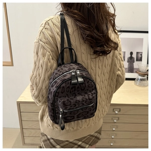 Detail of a mini leopard print backpack with grey textured fabric and black leather trim