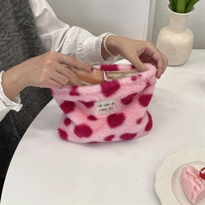 Macro view of plush makeup bag capacity showing a hand placing foundation inside