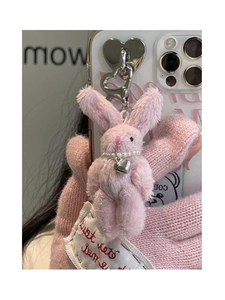 Detailed view of plush pink bunny charm with silver heart clip and pearl necklace detail