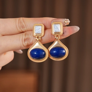 Macro shot of vintage gold earrings with navy blue resin and white marble stone detail