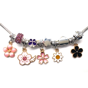 Detailed close-up of a DIY charm bracelet with colorful enamel flower and star pendants