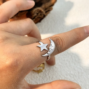 Silver star and crescent moon face open ring worn on finger in natural light