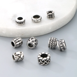Detailed close-up of vintage titanium steel cylinder beads with various engraved patterns