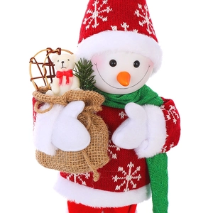 Detail of a Christmas snowman plush wearing a red knit sweater holding a burlap gift bag