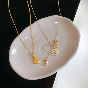 Detail of gold lucky bag and heart pendants with zircon inlay on decorative plate