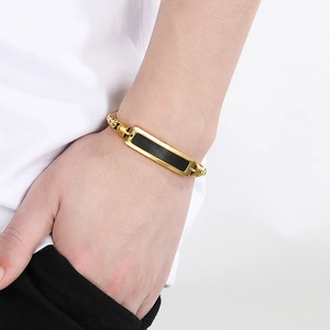 Nahaufnahme eines goldenen Herrenarmbands aus Edelstahl mit schwarzem Strich-Detail