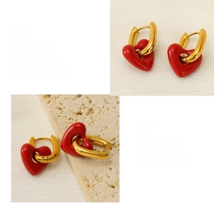 Macro detail of red heart drop earrings with gold hoops on a textured stone display