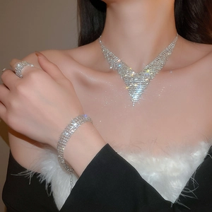 Detailed view of silver luxury V-shaped necklace, bracelet, and ring set with crystals
