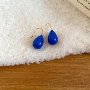 Élégantes boucles d'oreilles goutte bleu Klein avec crochets dorés sur fond blanc