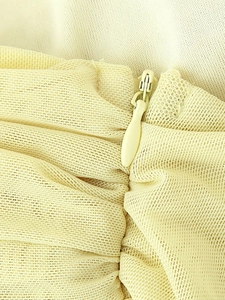 Detail of light yellow mesh fabric featuring an invisible zipper and pleated texture