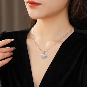 Detail of silver ginkgo leaf necklace with blue cloud pattern pendant and pearl on neck