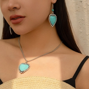 Close-up of bohemian heart-shaped turquoise necklace and earring set on model
