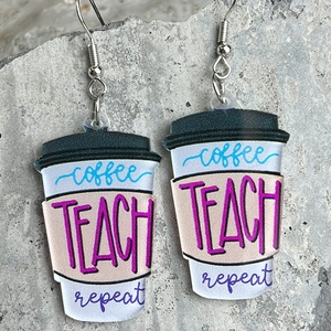 Détails macro des boucles d'oreilles tasse à café avec inscription Coffee Teach Repeat