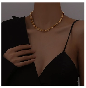 Close-up of elegant 18K gold-plated knot chain necklace worn on neck by a model