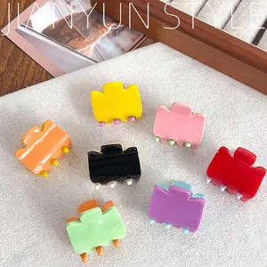 Set of seven colorful mini acrylic hair claws in vibrant candy colors on linen fabric