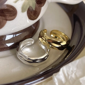 Detailed view of two irregular foil texture open rings in polished gold and silver finish