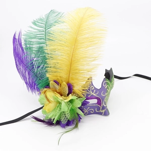 Detail of purple masquerade mask with vibrant feathers, yellow flowers and gold glitter patterns