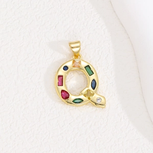 Detailed macro of gold letter Q pendant with multi-colored cubic zirconia stones