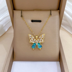 Detailed view of a gold butterfly necklace with blue opal wings and zircon accents