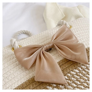Detail of light brown silk bow on woven straw tote bag with rustic hemp rope handle