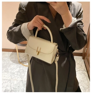 Detail of off-white minimalist square crossbody bag with gold pillar lock and top handle