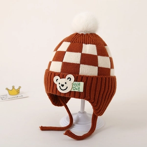 Detail van de gebreide baby wintermuts met ruitpatroon en schattige beer patch