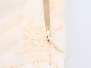 Detail eines unsichtbaren Reißverschlusses und Stickerei an einem weißen Kleid
