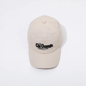 Detalle de gorra beige con bordado negro Chi Omega y logotipo de cara sonriente