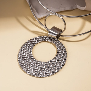 Detail of silver geometric textured pendant on a multi-layer metal choker necklace