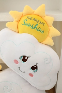 Close-up of plush white cloud pillow with embroidered You Are My Sunshine sun detail