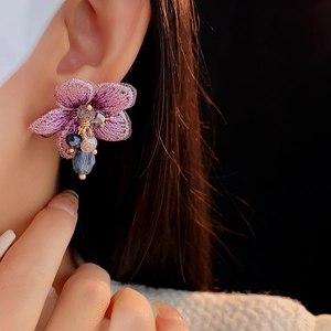 Primo piano dell'orecchino a fiore in tessuto viola con perline di cristallo