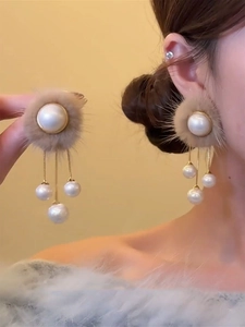 Vue détaillée des boucles d'oreilles pompon beige avec perles et chaîne dorée