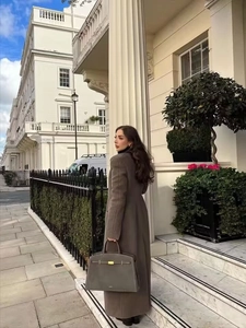 Detail eines braunen Wollmantels mit passender Handtasche vor klassischer Londoner Kulisse