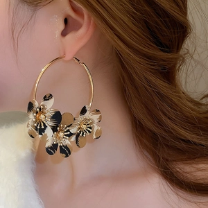Close-up of leopard print fabric floral hoop earrings on model with golden finish