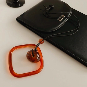 Detail of wax cord necklace with amber square frame and round resin bead pendant
