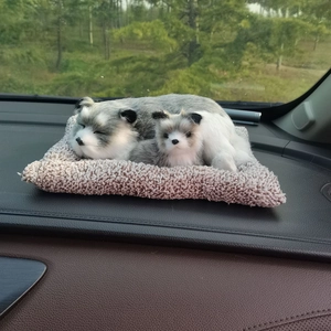 Realistic plush cat dolls on beige mat displayed on a car dashboard as interior decoration