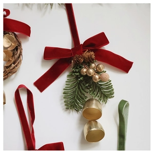 Close-up of Christmas hanging ornament with red velvet bow and golden metal bells