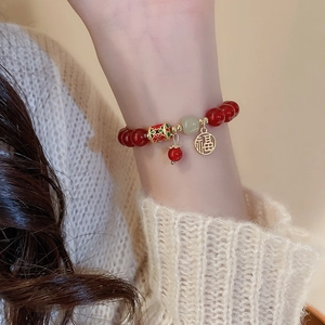 Gros plan d'un bracelet en perles rouges avec pendentif Fu doré et décor émail