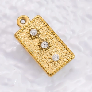 Detailed macro of 18K gold rectangular tarot pendant with three white zircon stars