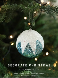 Gros plan d'une boule de Noël bleue et blanche sur sapin avec lumières bokeh