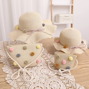 Close-up of straw hat and bag set with colorful pom-pom decor on white lace