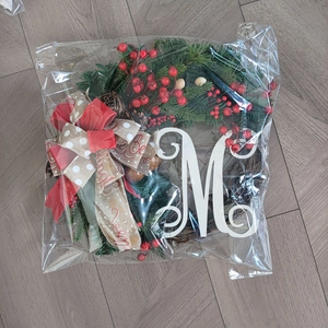 Detail of a Christmas wreath with red berries and letter M in transparent packaging