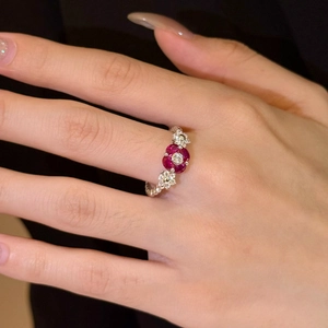 Detail of vintage floral ring with red zircon petals and textured silver twisted band