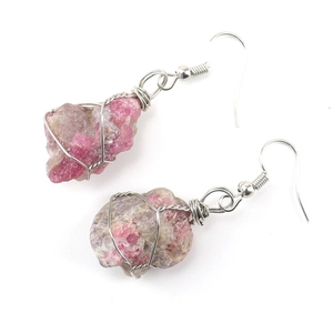 Macro detail of handmade silver wire wrapped raw pink tourmaline crystal earrings
