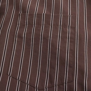 Detailed view of brown striped fabric texture and pocket stitching of the casual shirt