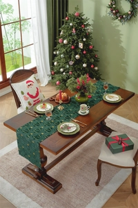 Close-up of dark green velvet Christmas table runner with gold tree and star patterns