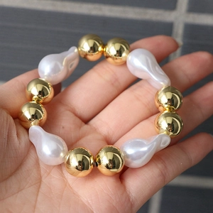 Detail of baroque pearl and gold bead adjustable bracelet displayed on a palm