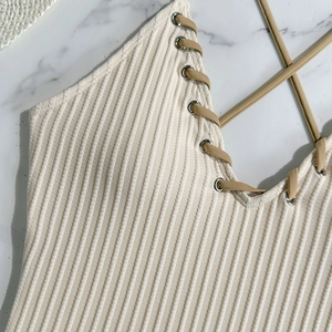 Detail of cream ribbed one-piece swimwear with deep V-neck and khaki crisscross drawstrings