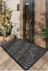 Detailed texture of black rubber door mat with leaf pattern in front of a modern villa