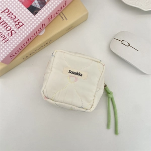 Detailed view of soft quilted cream mini sanitary napkin storage pouch with tassel